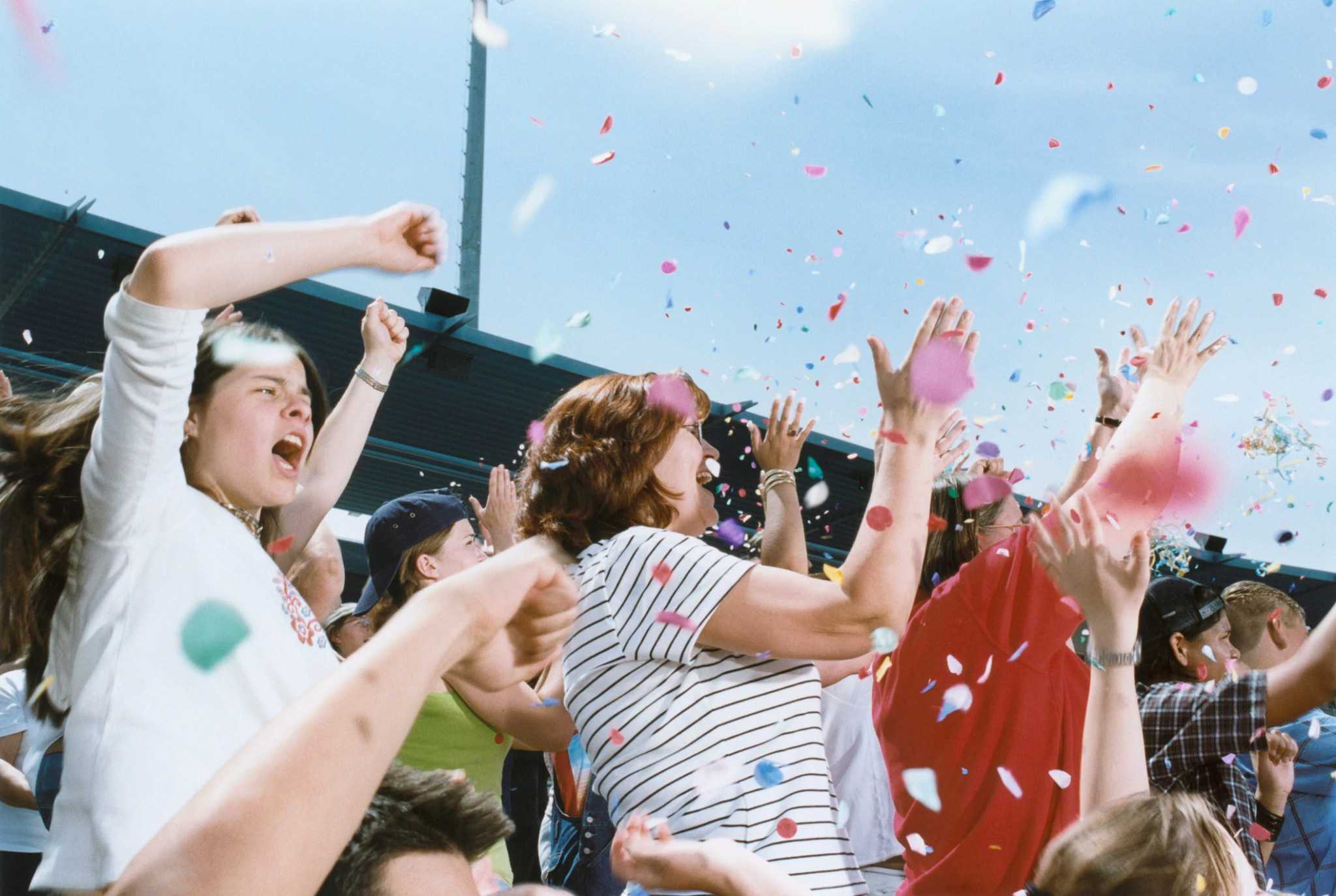 a group of people cheering at a gane with confetti in the air
