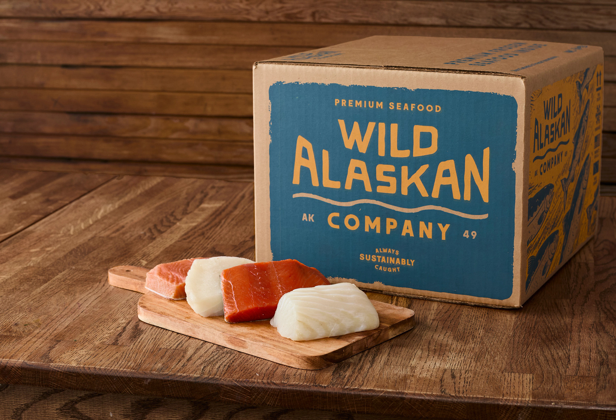Raw seafood on a cutting board next to a Wild Alaskan Company box