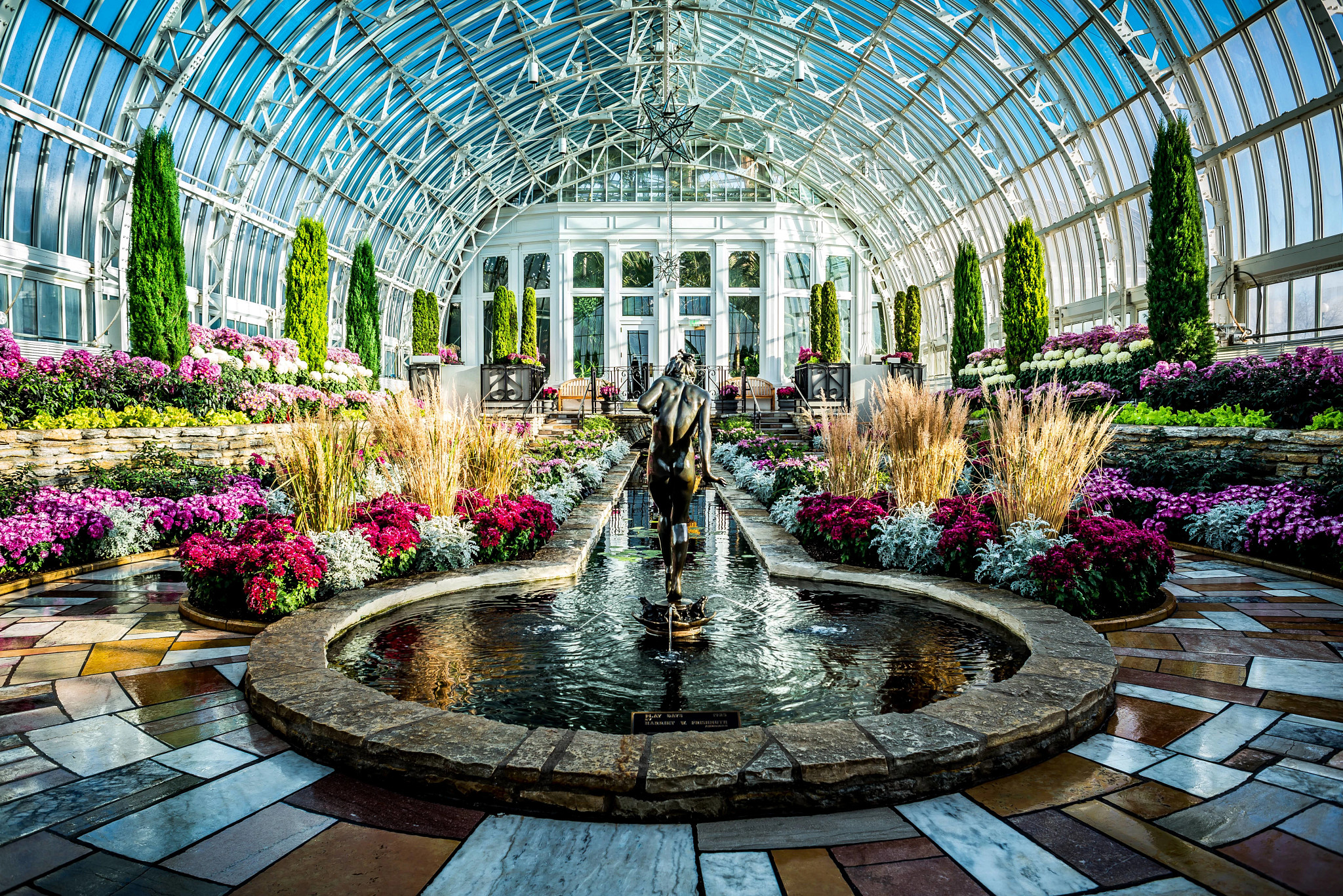 a statue in the middle of a pond inside a conservatory