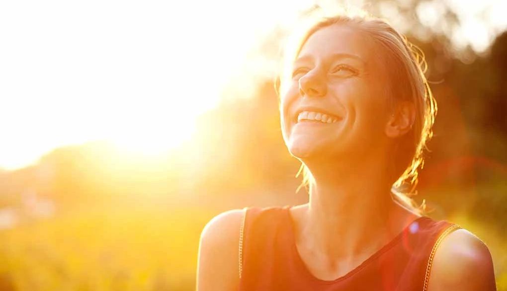 Sunshine triggers brain chemicals that can help regulate your sleep-wake cycle A woman smiling as the sun shines on her