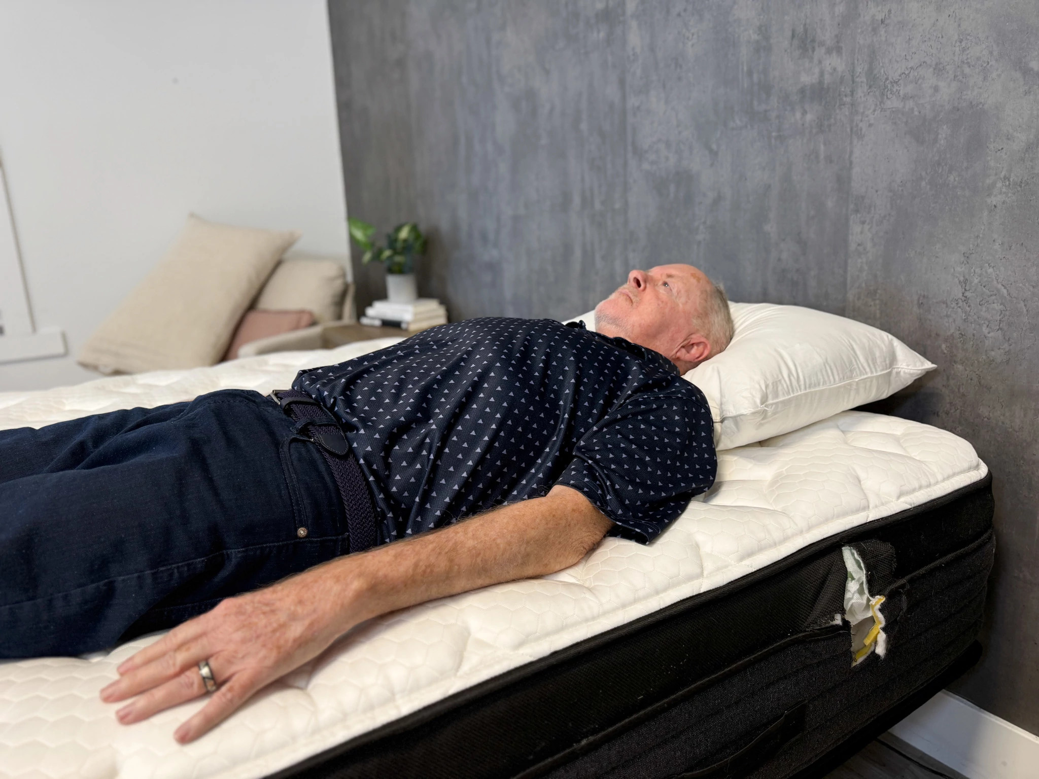 Man lies on his back on a mattress and looks upward