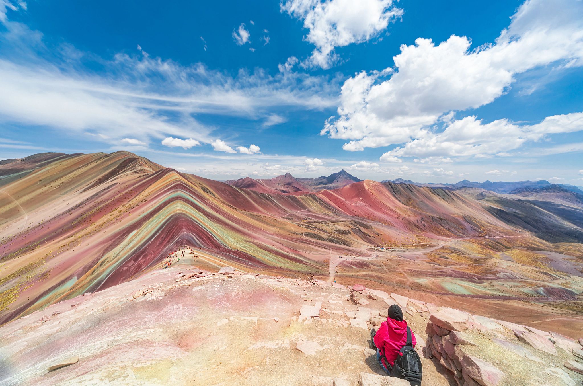 Cusco Peru a person sits facing multi-colored mountain dunes