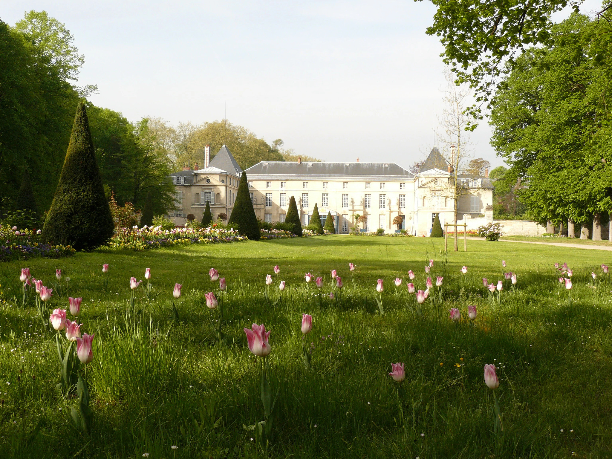 Castillo de Malmaison con flores rosas en el jardín delantero