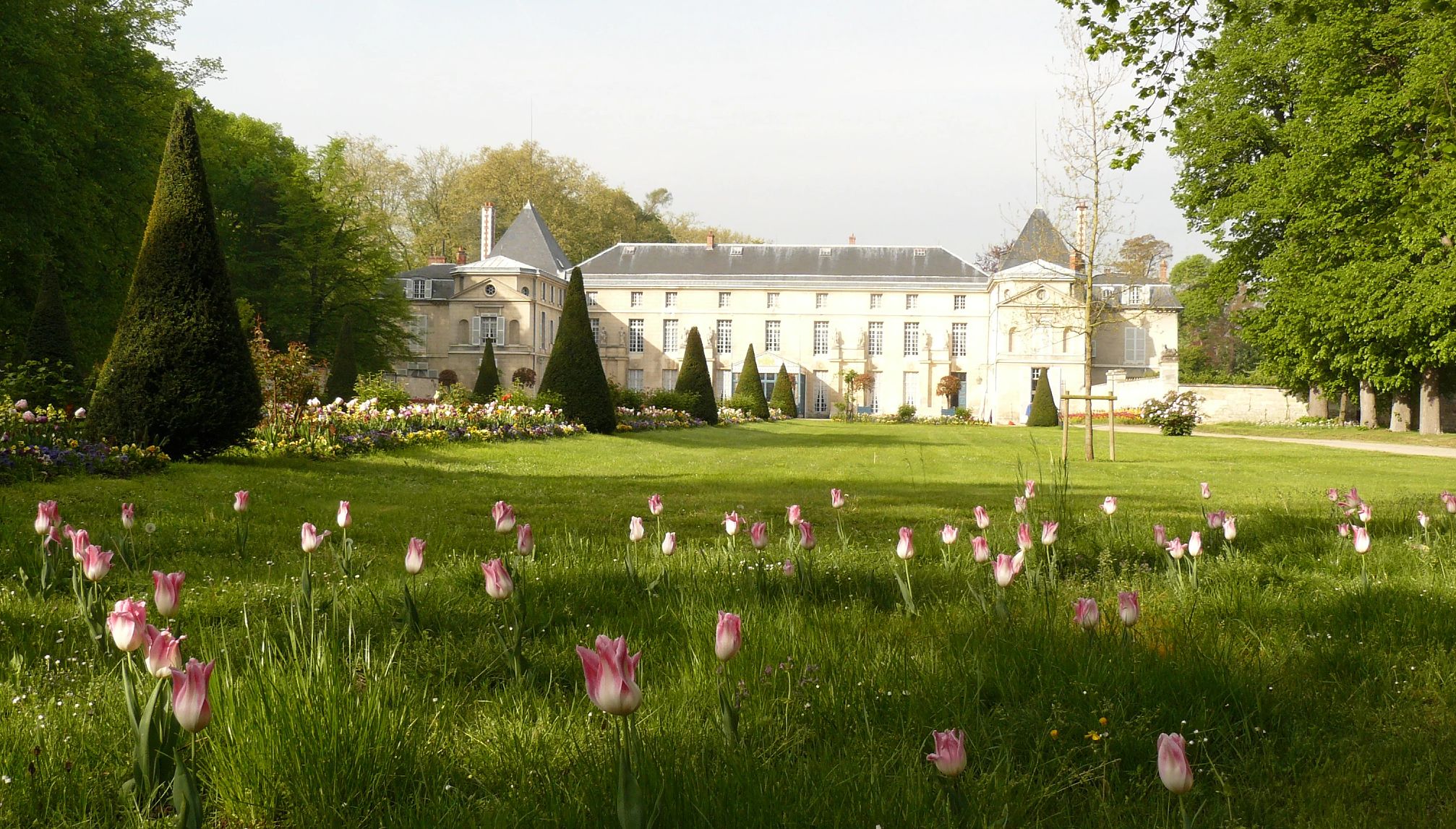 Castillo de Malmaison con flores rosas en el jardín delantero