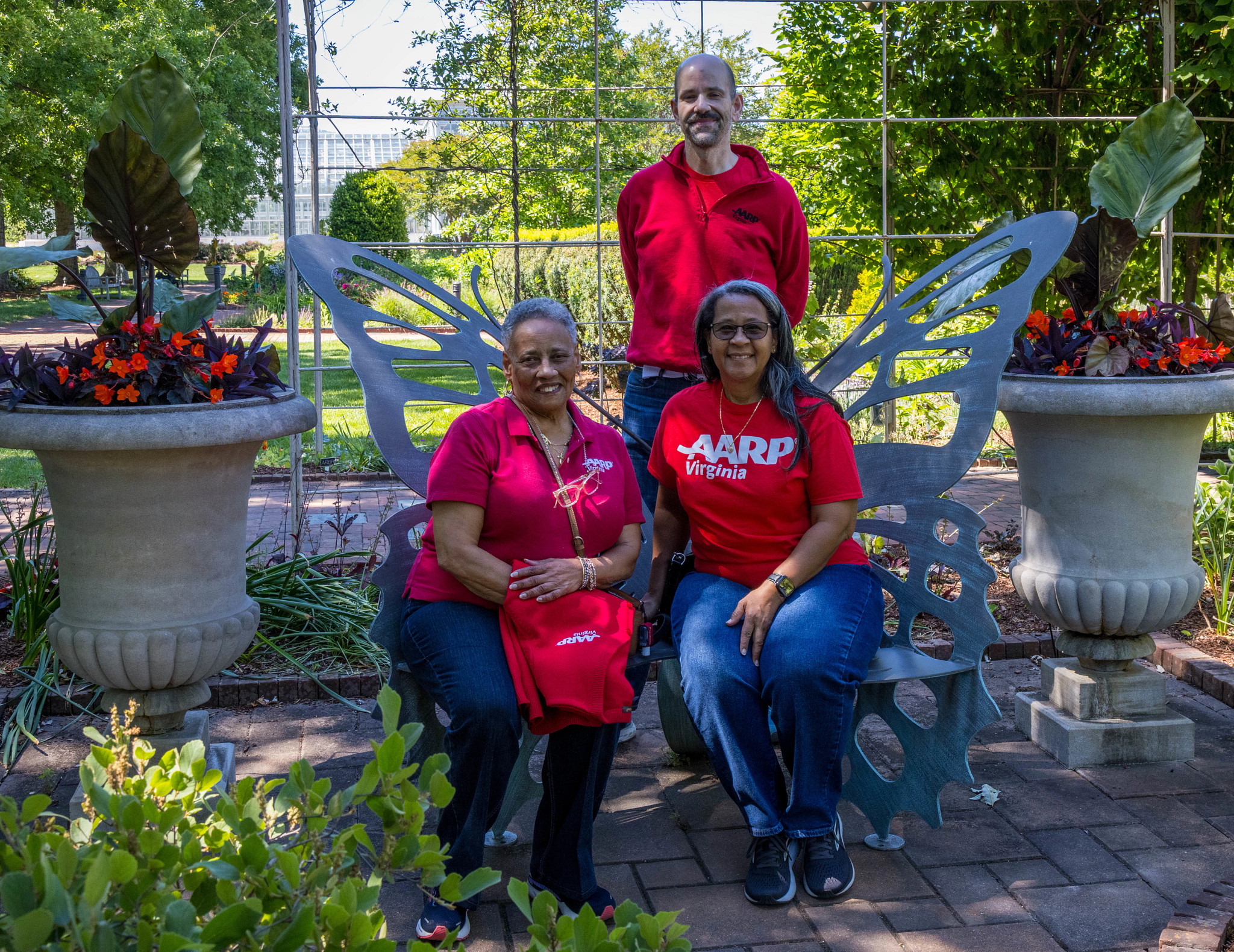 AARP Virginia staff takes picture with botanical garden staff on a butterfly bench
