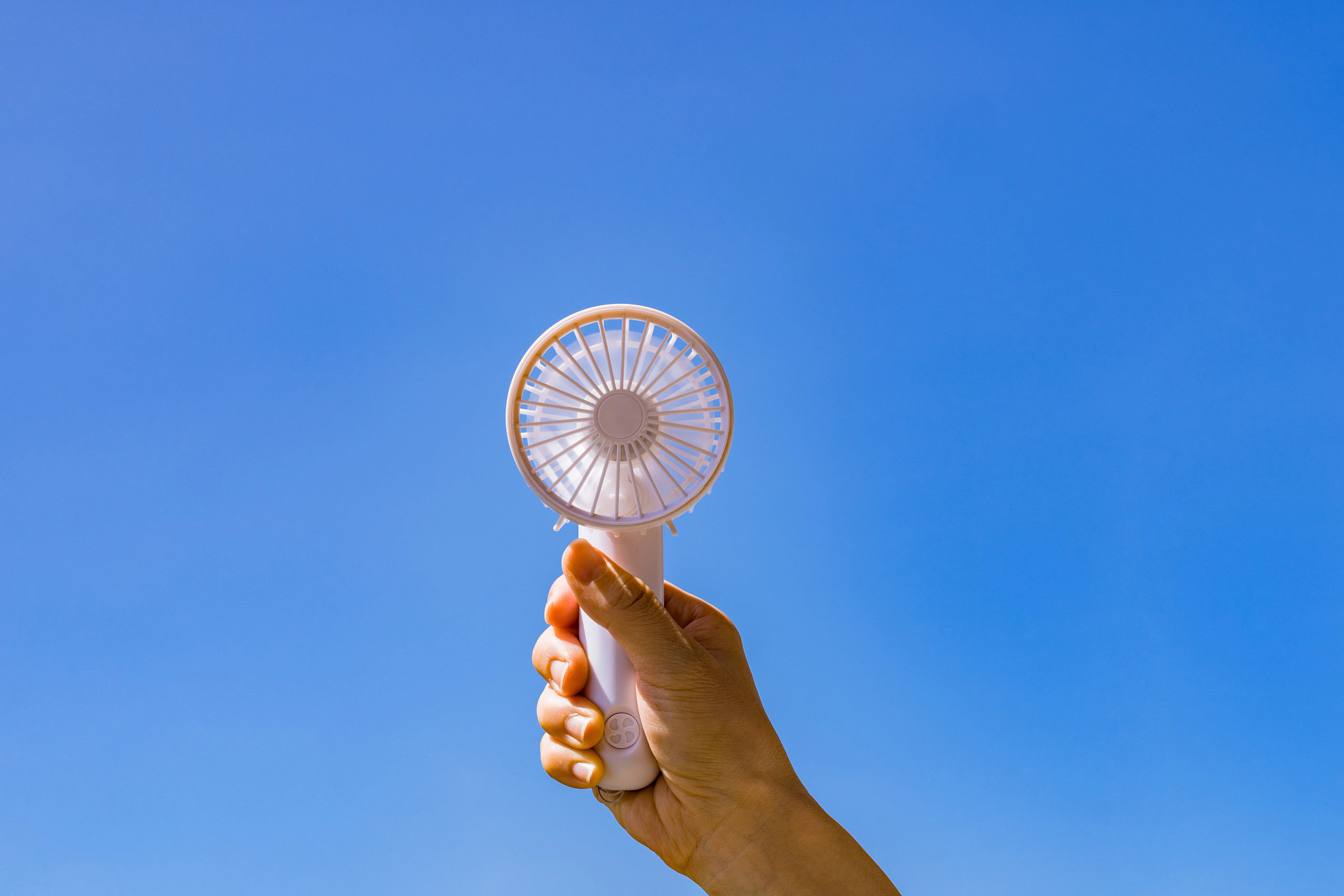 a person's hand holding a portable fan