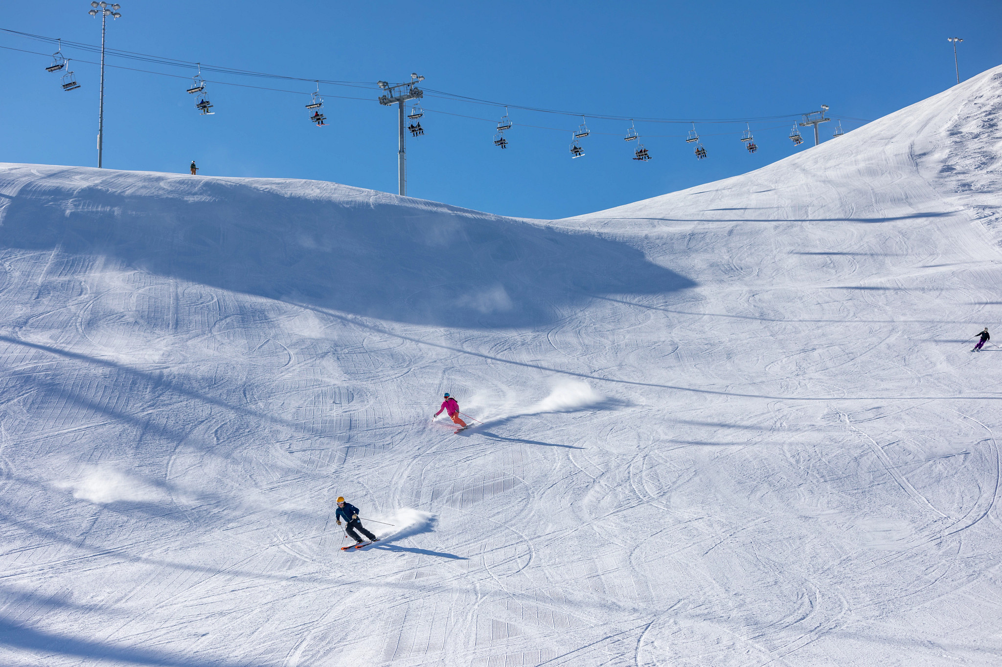 people skiing down a mountain with a ski lift at the top