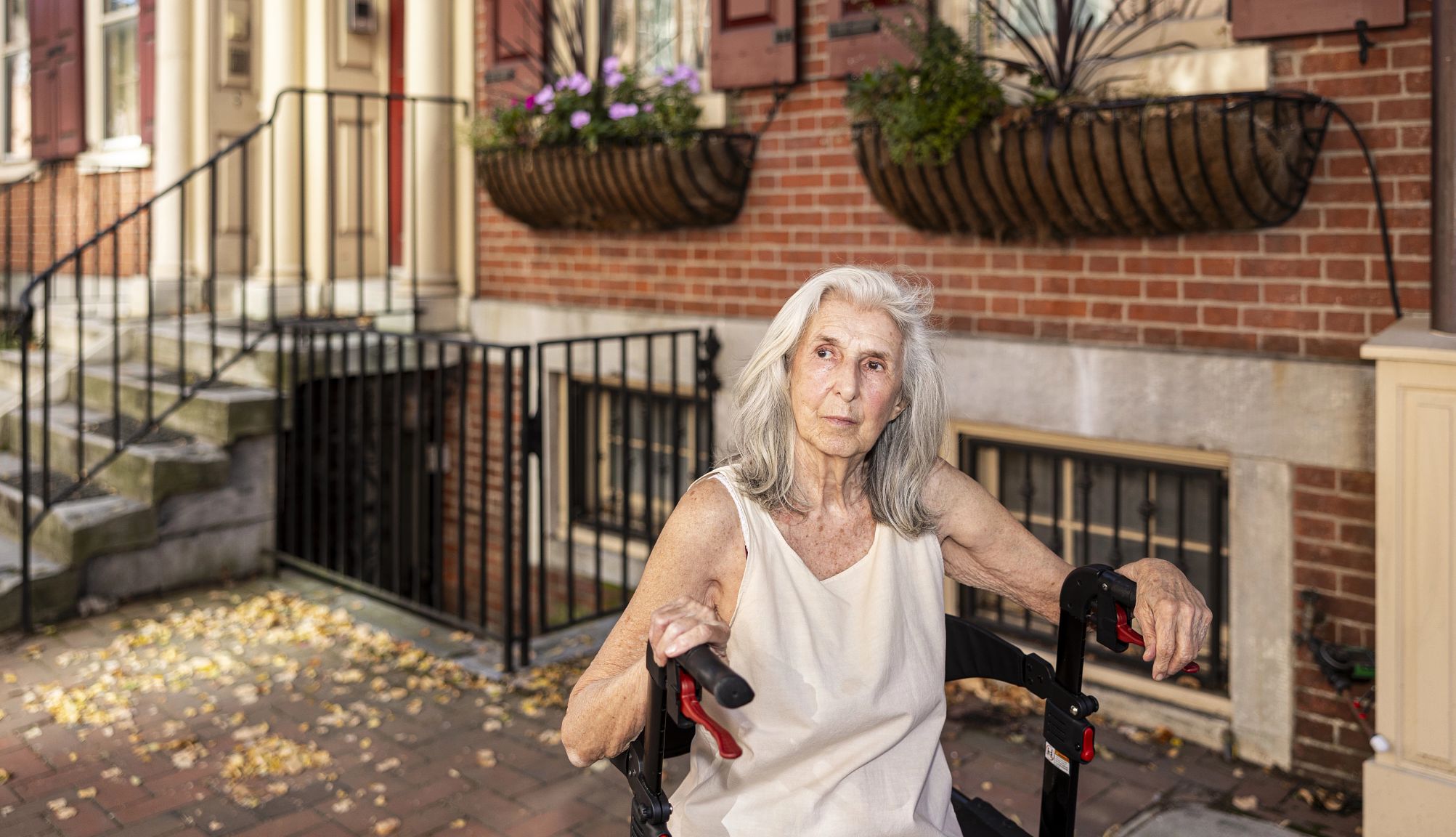 Norma Kramer a woman looks into the distance in front of a brick building
