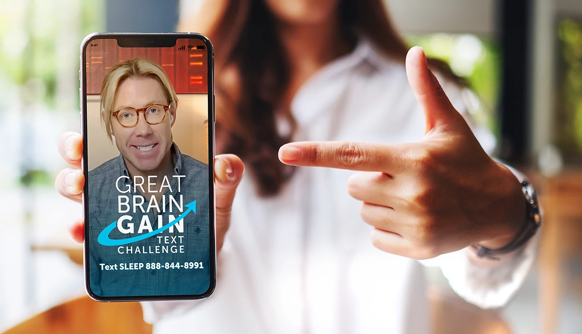 Join sleep expert Matt Walker, PhD, best-selling author and sleep scientist in our sleep text challenge A woman pointing at a held out phone showing the image of a man and the text "Great Brain Gain Text Challenge"