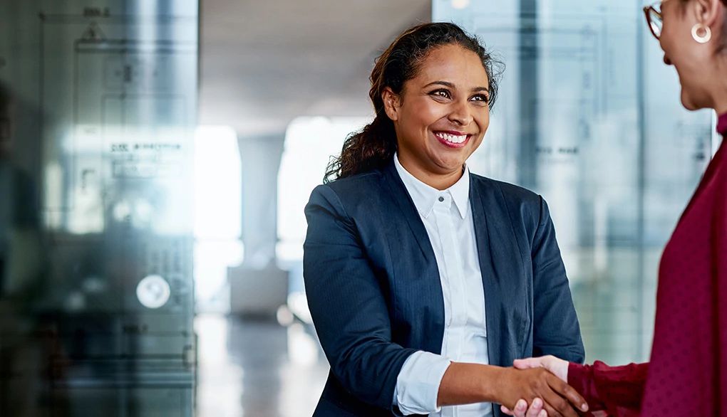 Remember new names by repeating them Two businesswomen shaking hands with each other in an office building