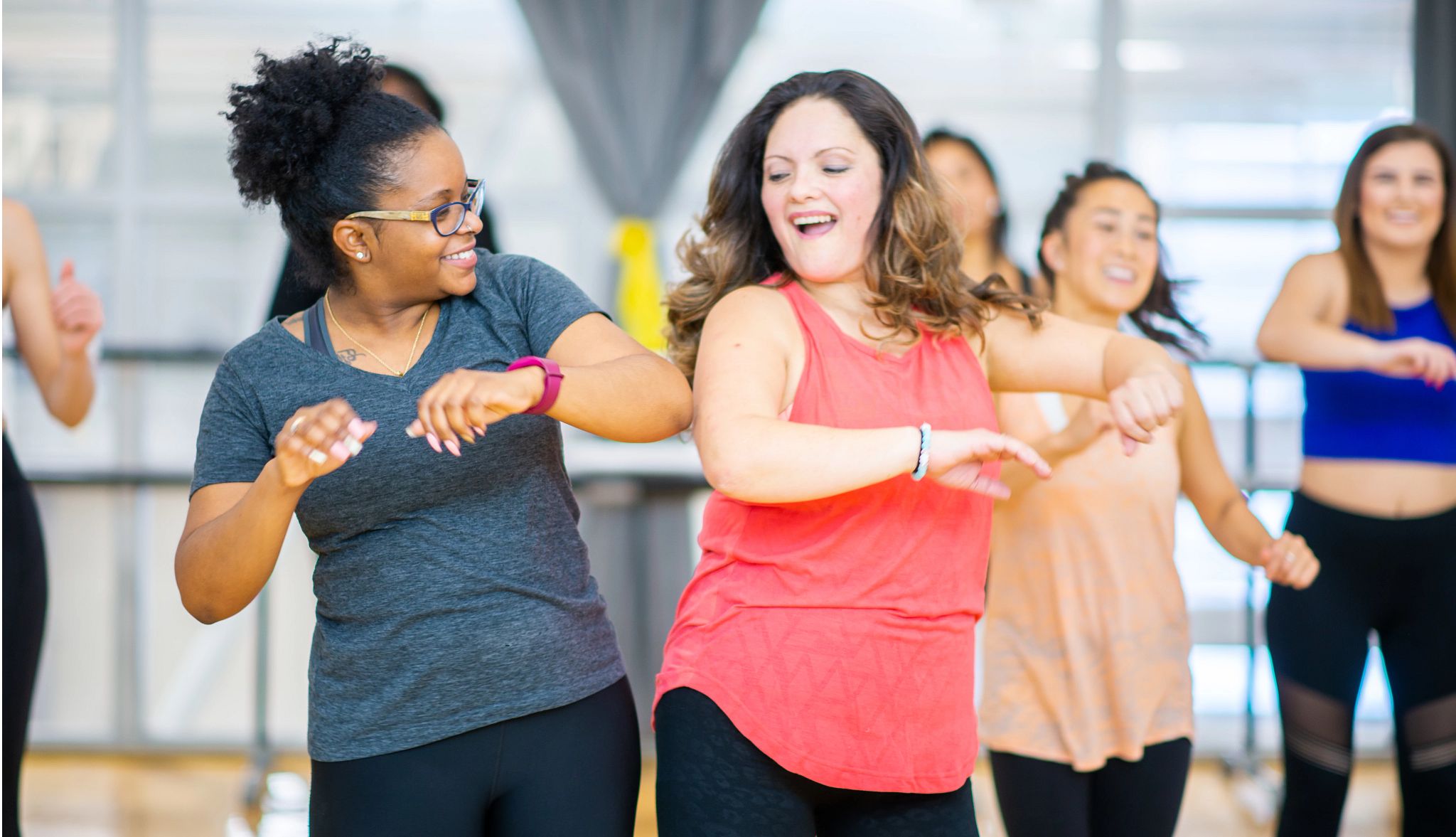 Two women in an exercise class bumping hips Two women in an exercise class bumping hips