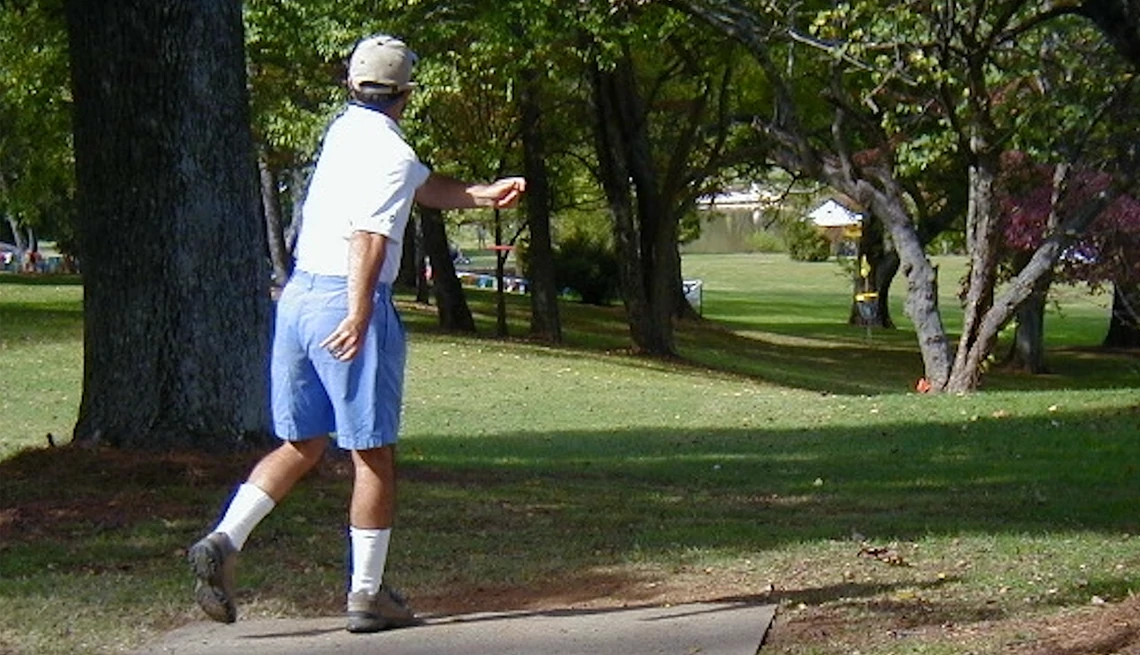 a man throwing a disc at a disc golf course