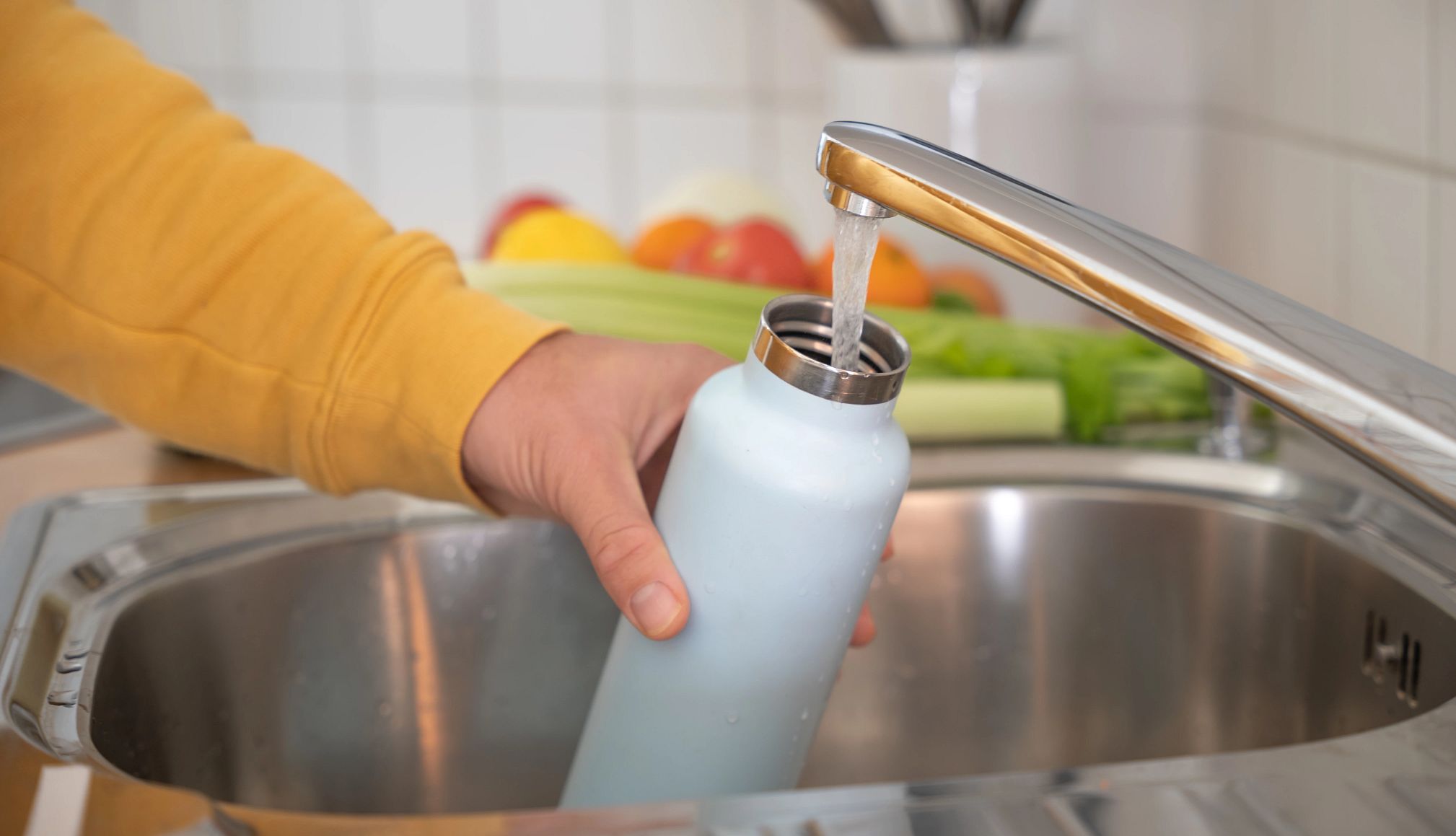 Una mujer lava una botella de agua reusable