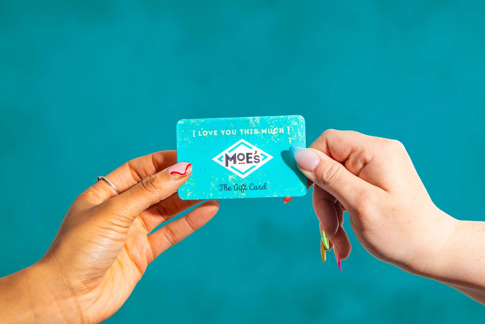 two hands holding a Moe's Southwest Grill gift card