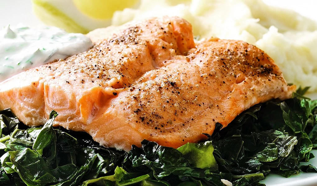 A close-up view of an arctic char on a bed of kale