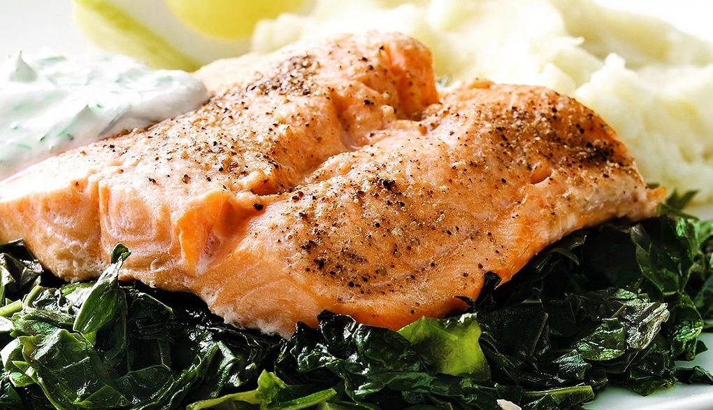 Arctic char on a bed of kale A close-up view of an arctic char on a bed of kale