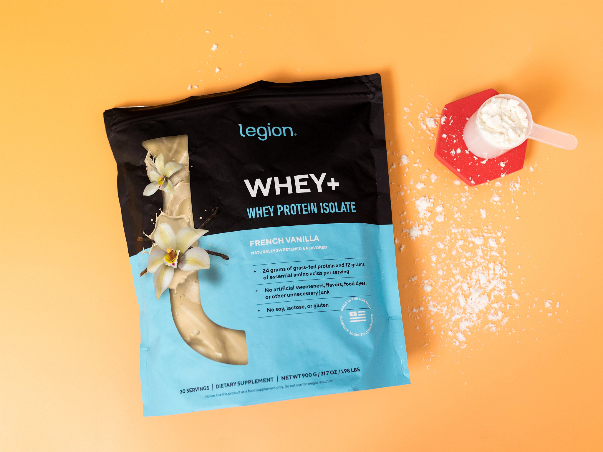 A bag and scooper of Legion Whey+ Grass-Fed Protein Isolate on an orange background