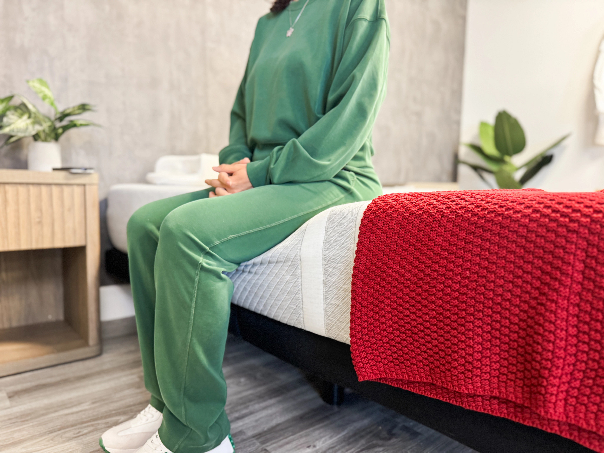 Woman sits on the edge of a mattress with her hands folded in her lap