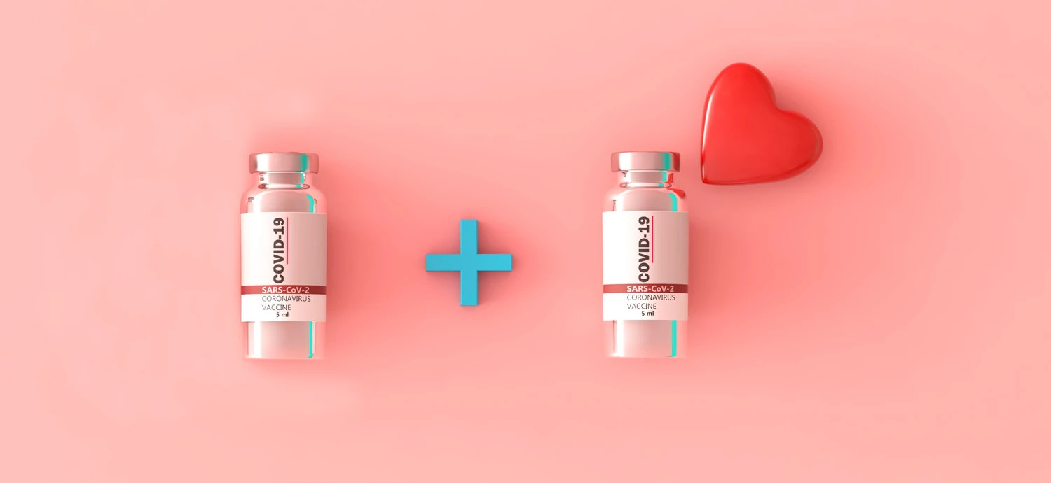 conceptual 3D illustration on a pink background featuring two vials of SARS-CoV-2 coronavirus vaccine. Between the two vials is a blue plus sign, and a red heart is positioned to the right of the second vial