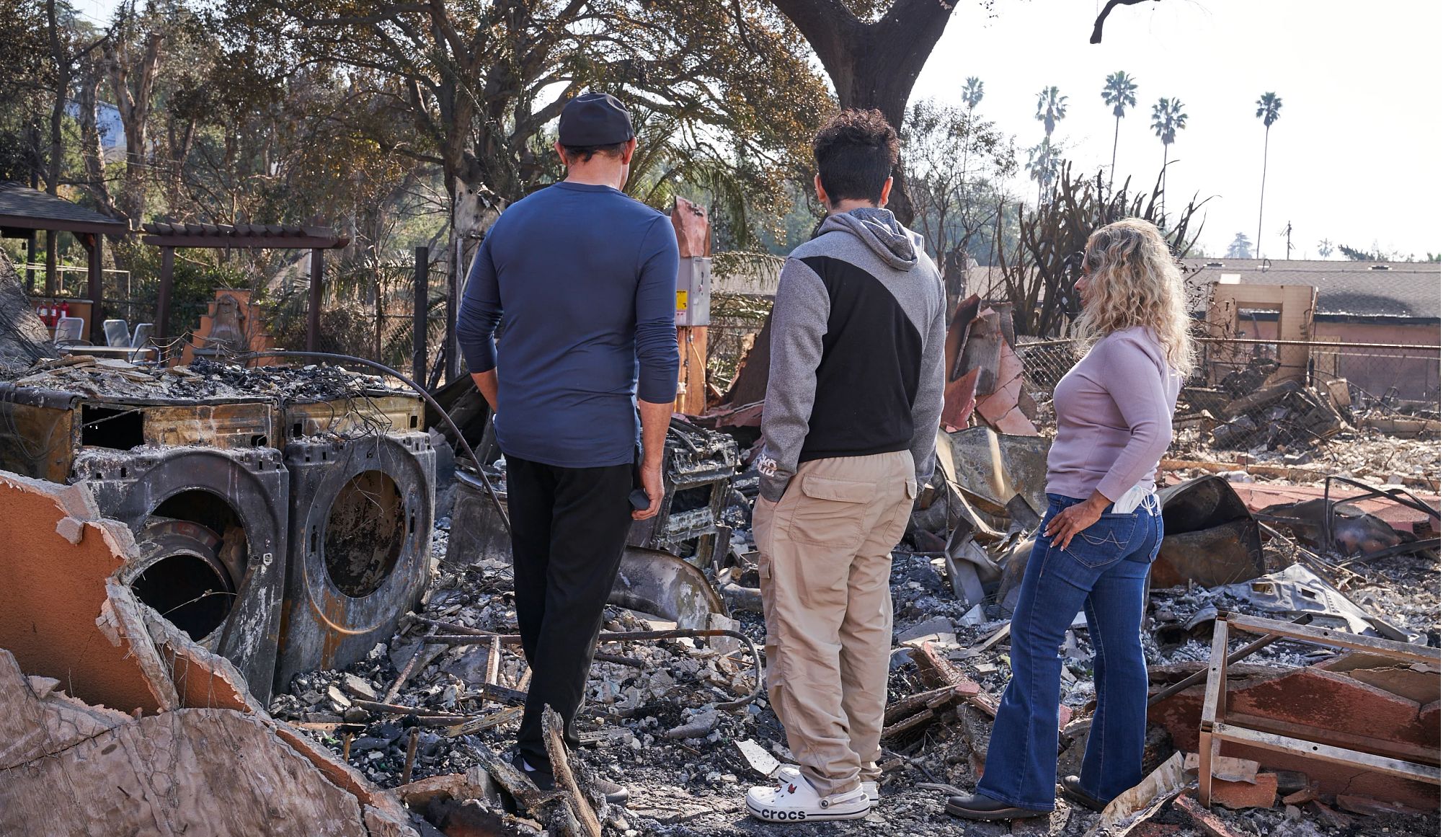 Ways to Regain Your Financial Footing After a Natural Disaster people look at the burned ruins of their home after a fire