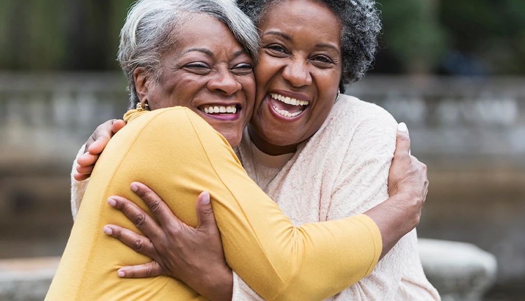 Rekindling friendships may support health and well-being Two women smiling and hugging each other