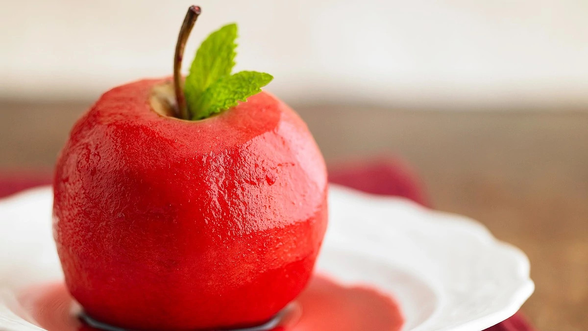 A close-up view of a cherry-wine poached apple on a plate
