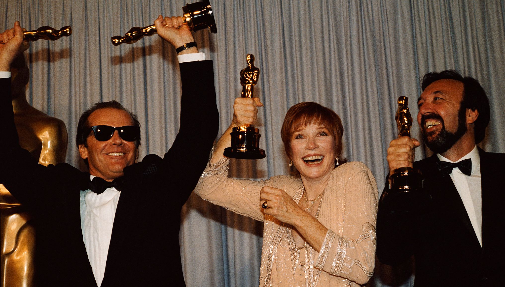 Jack Nicholson, Shirley MacLaine y James L. Brooks sostienen sus premios Óscar.