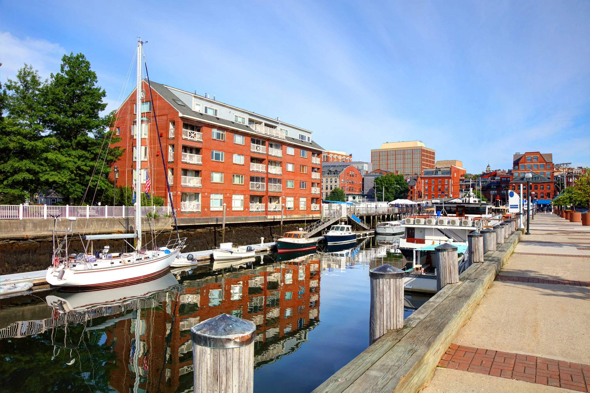 boats in a port near buildings and a walkway