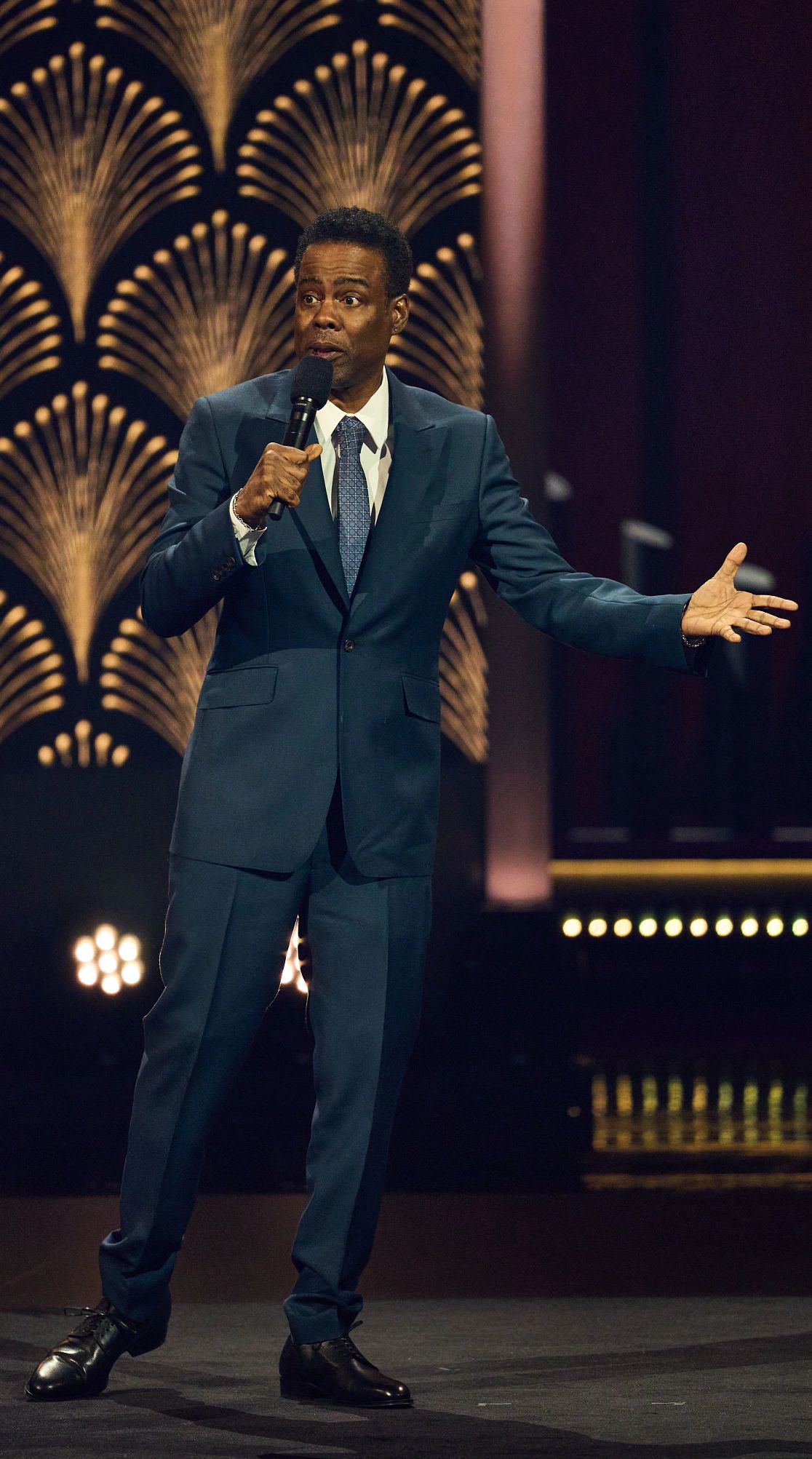 Chris Rock talking into a microphone onstage at the 25th Annual Mark Twain Prize For American Humor