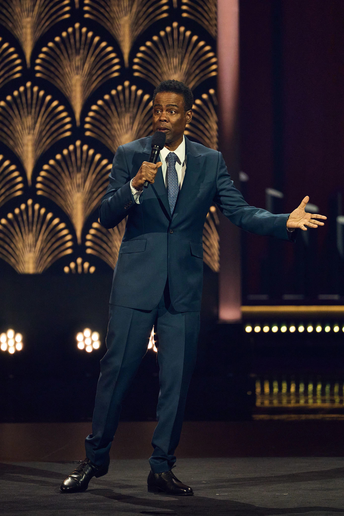 Chris Rock talking into a microphone onstage at the 25th Annual Mark Twain Prize For American Humor