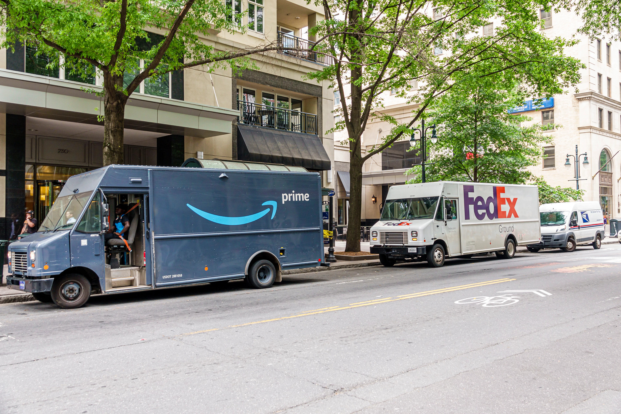 An Amazon Prime truck and FedEx truck are parked on the side of a street.