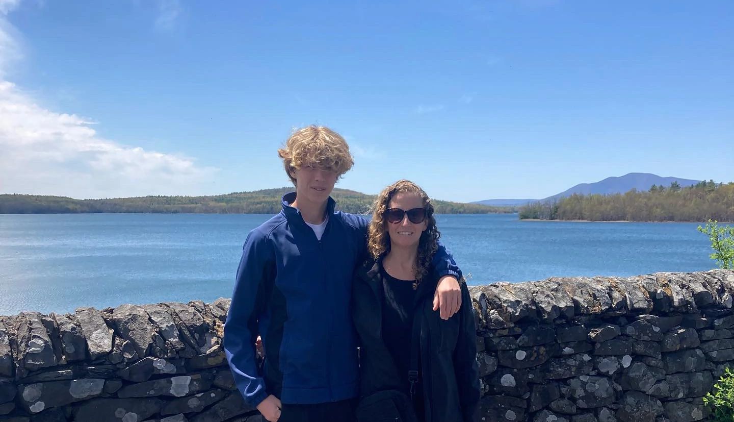Son and mom together on hike Son with arm around mom Aileen Weintraub; body of water in background