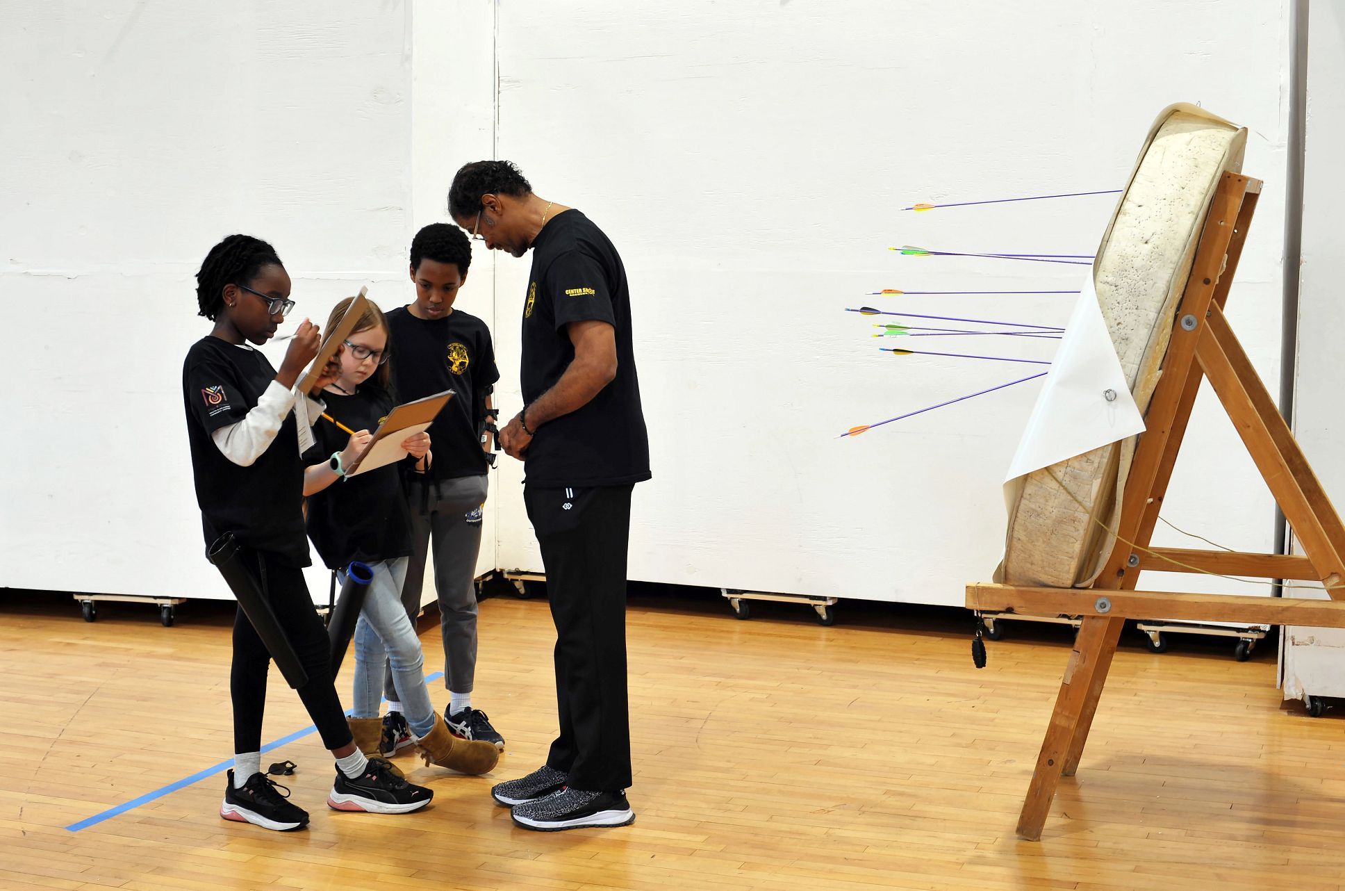 Both children and adults can benefit from archery Coach Philip Jefferson with archers and first-place winners Emily, Evelyn and Ben as they calculate their scores