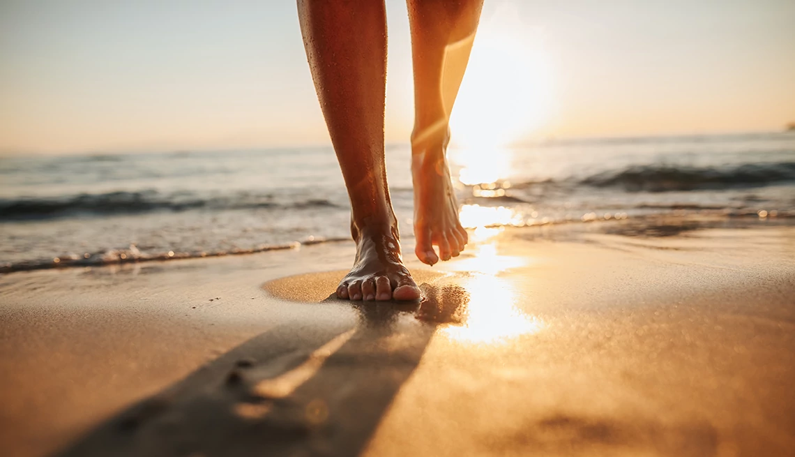 Bare feet walking on the beach A closeup of bare feet walking on the sand at the beach with the sun shining in the background