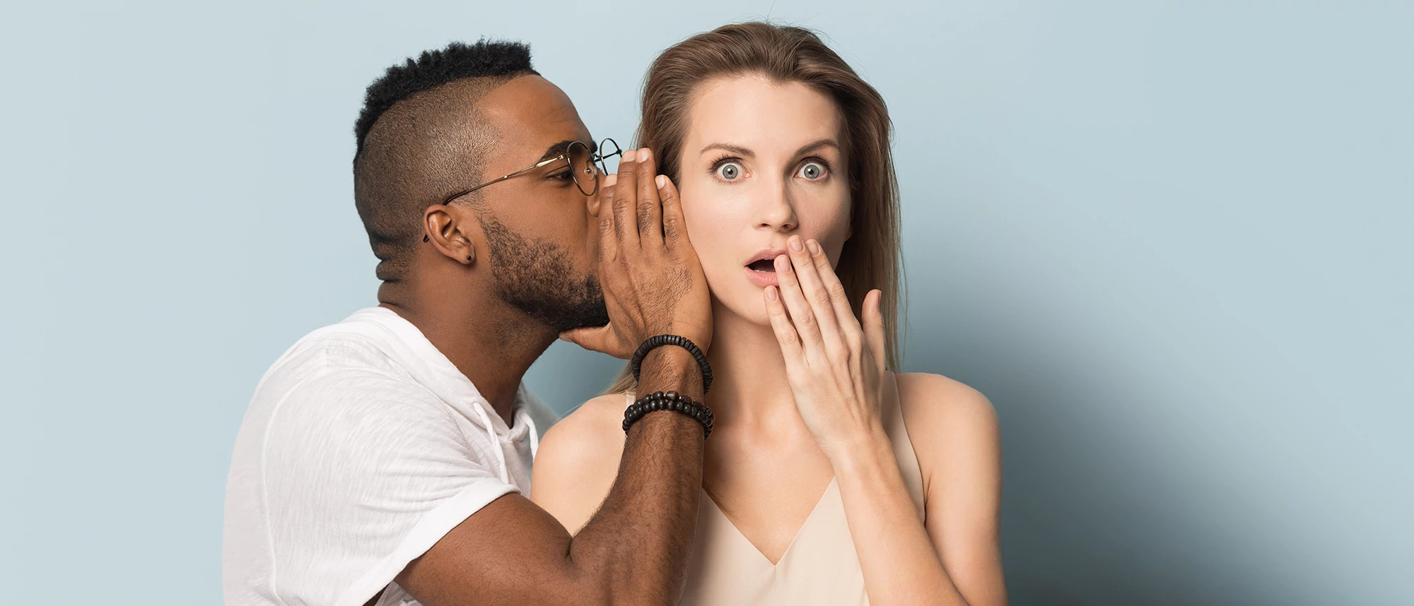 African American man tell secret to shocked caucasian female