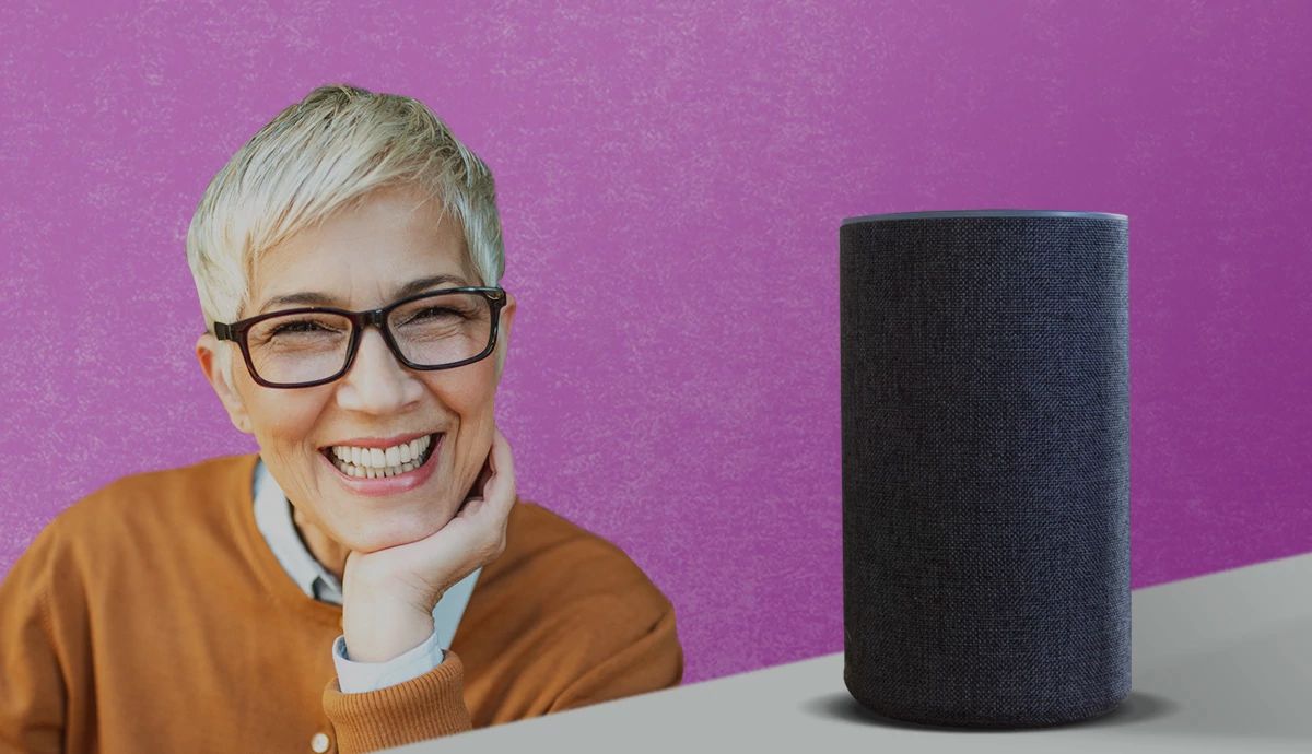 An older woman looking excited about her smart speaker sitting on the counter