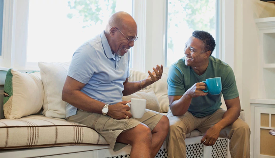 two older middle age men sitting, having coffee, talking