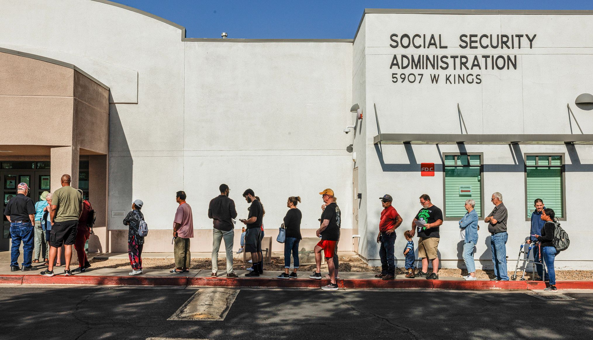 Una fila de personas espera para entrar a las oficinas del Seguro Social.