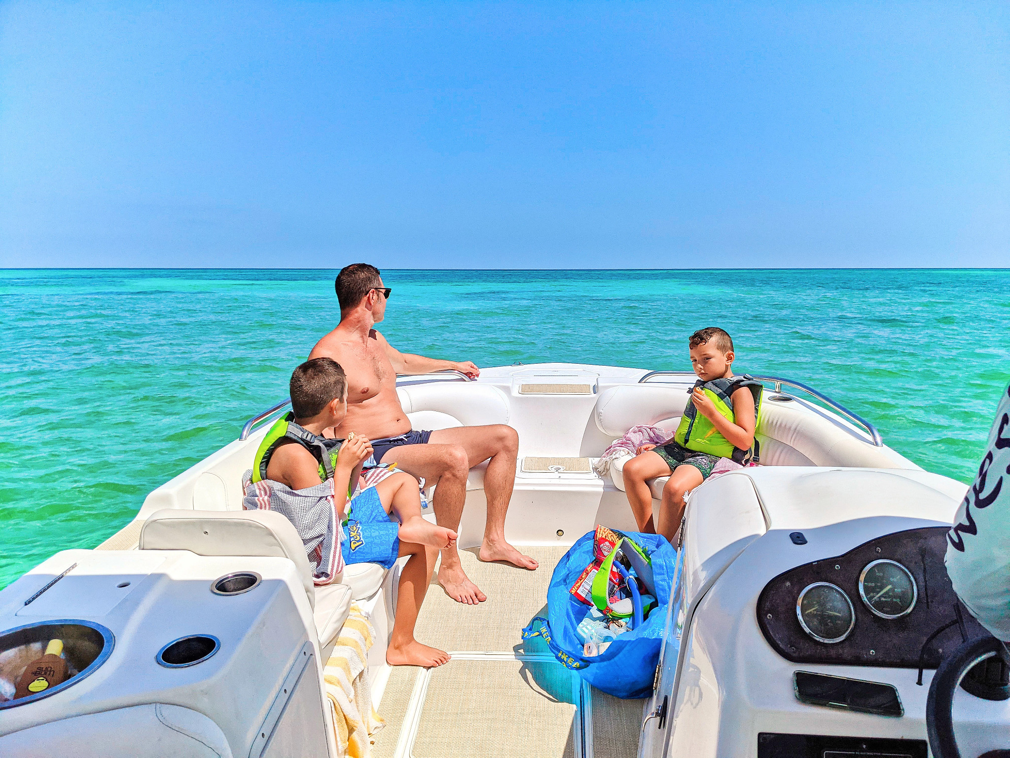 a family sitting on the back of a boat in the middle of the ocean