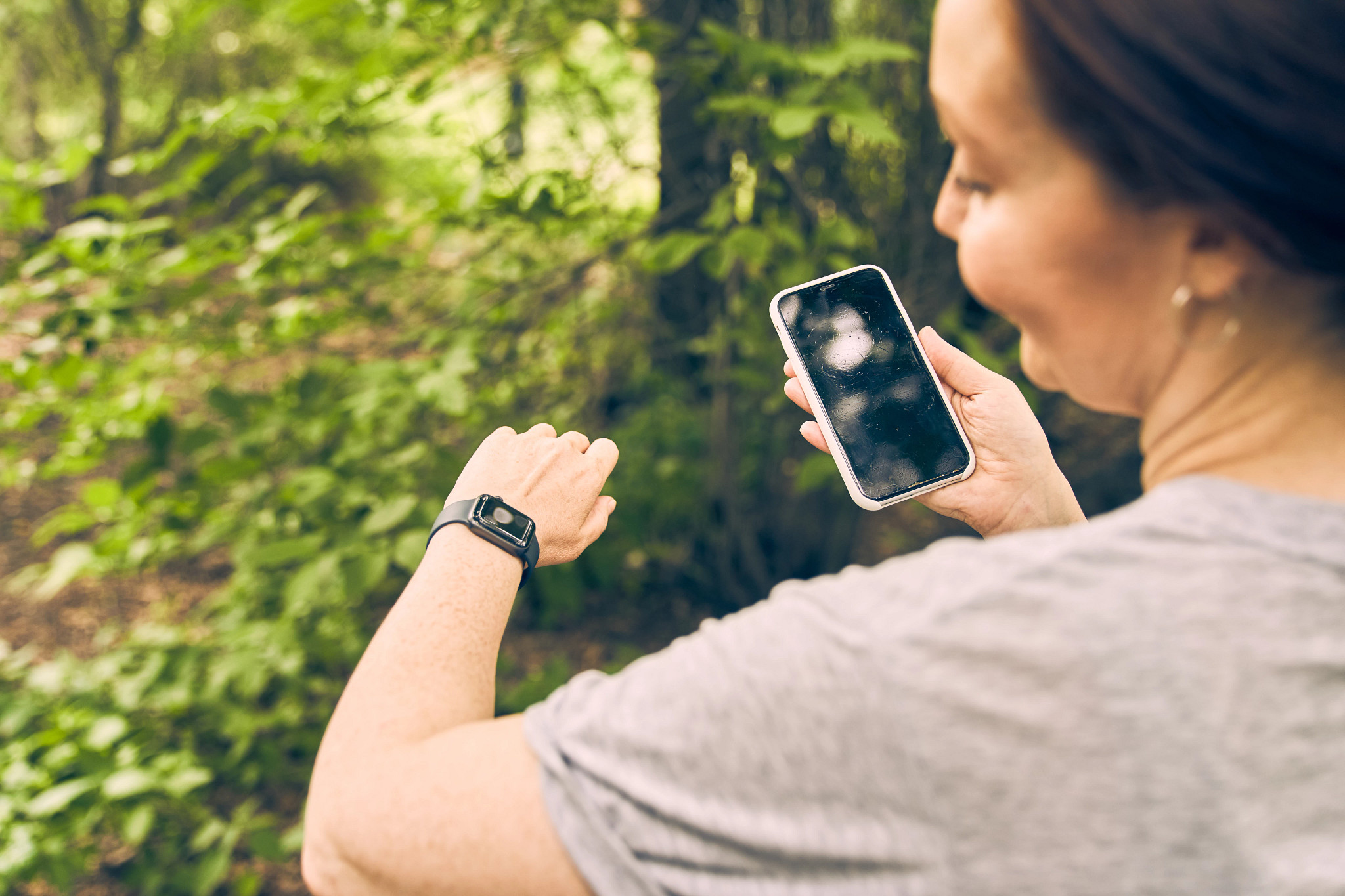 a woman looking at her smart watch and her smart phone