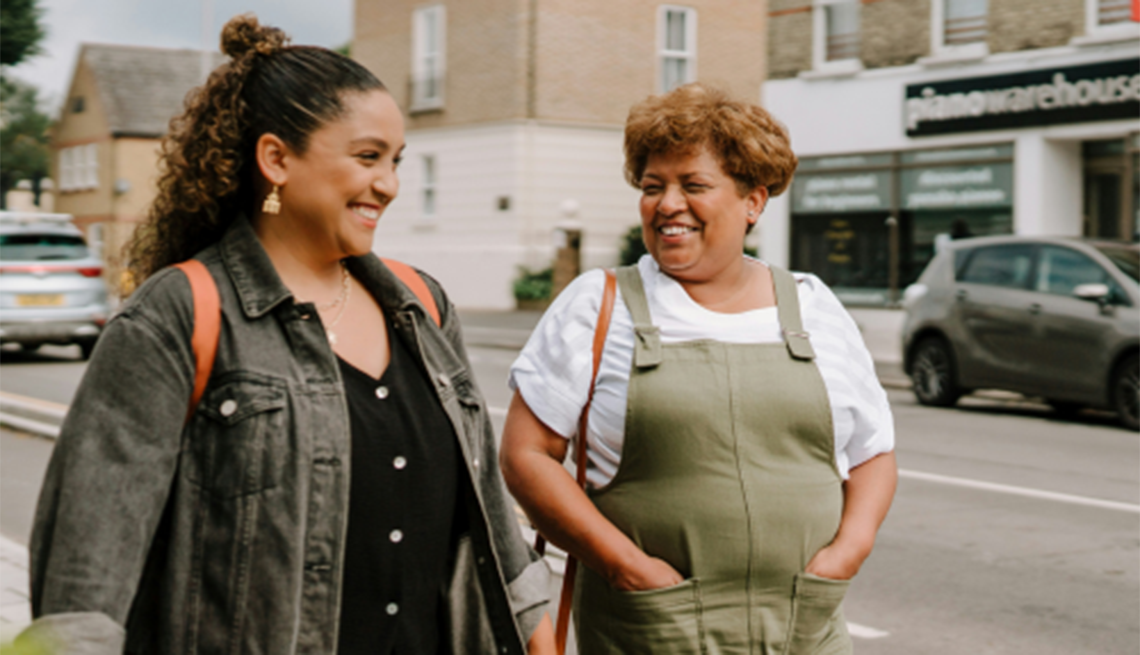 People should learn about brain health and strategies to build brain-healthy habits Two smiling women walking on a sidewalk in a town together