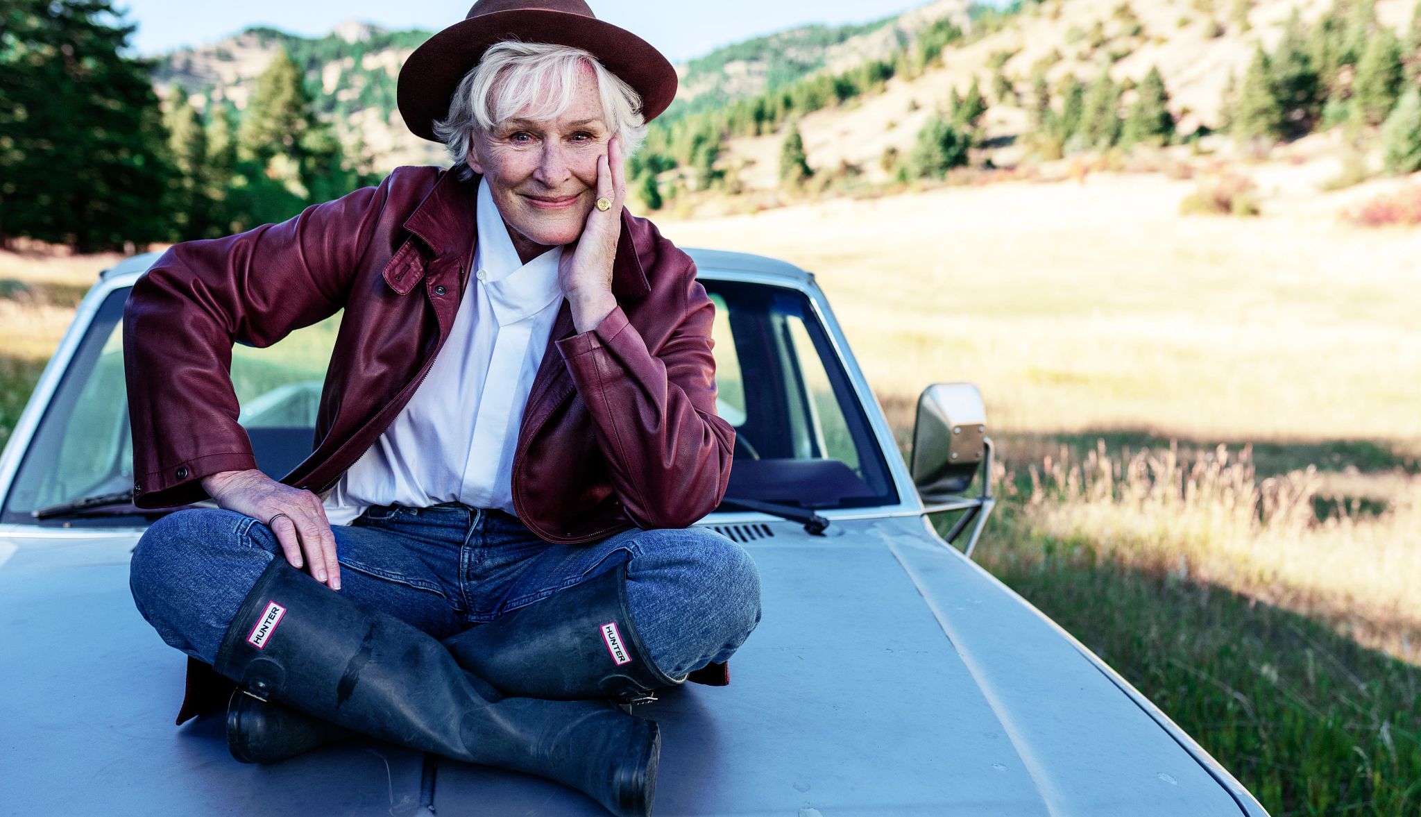 Glenn Close actor glenn close sits on the hood of a car, which is parked in the middle of open land
