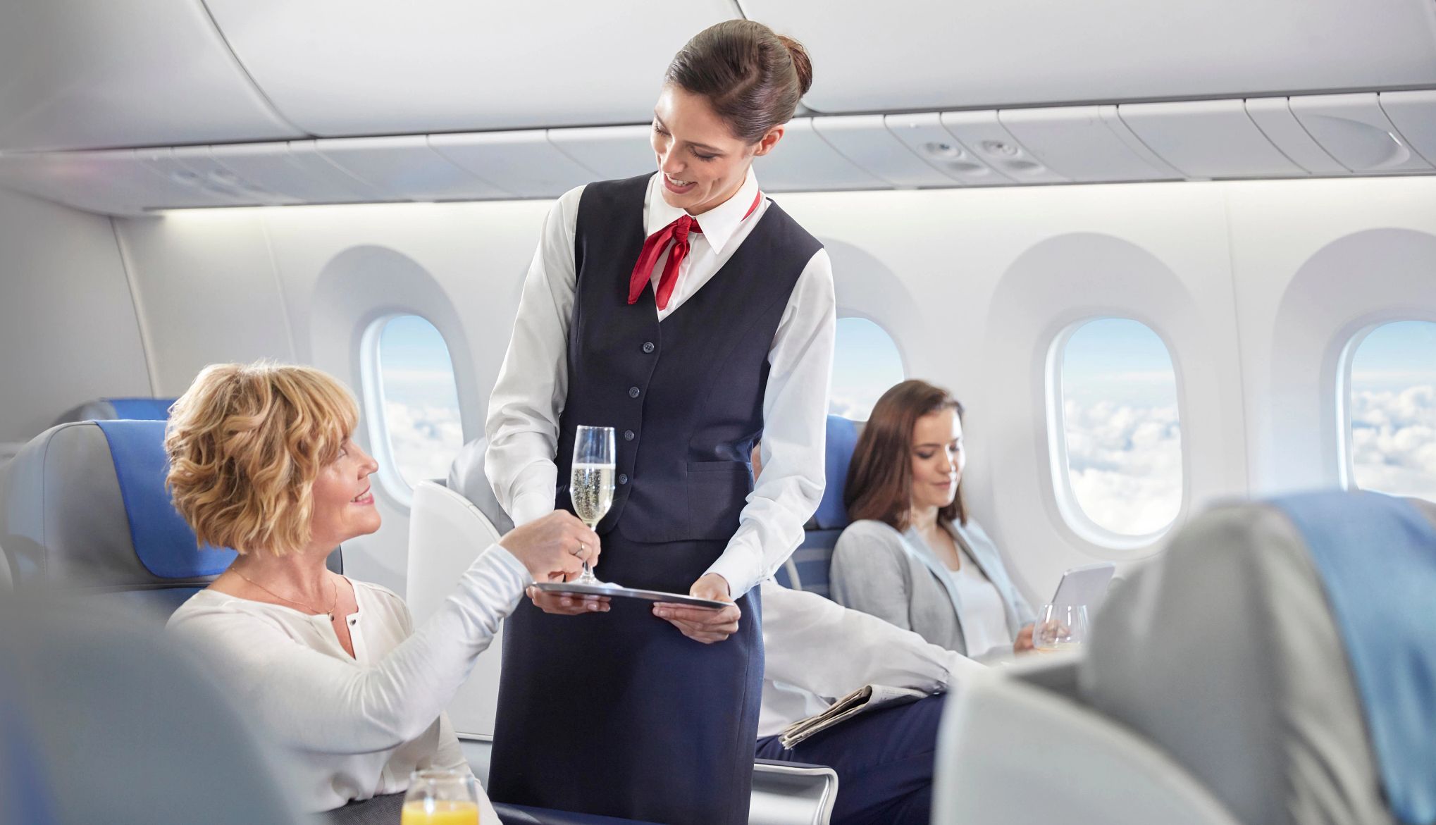 You may want to consider upgrading to first class on a long flight a woman sitting in first class is served a glass of champaigne