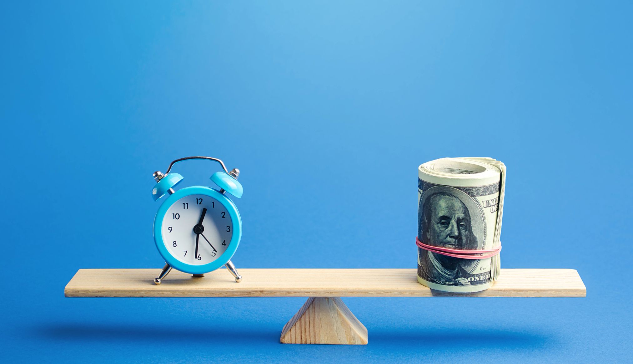 IRA Contribution Limits for 2025 vs. 2024 a balance with a roll of bills and a clock