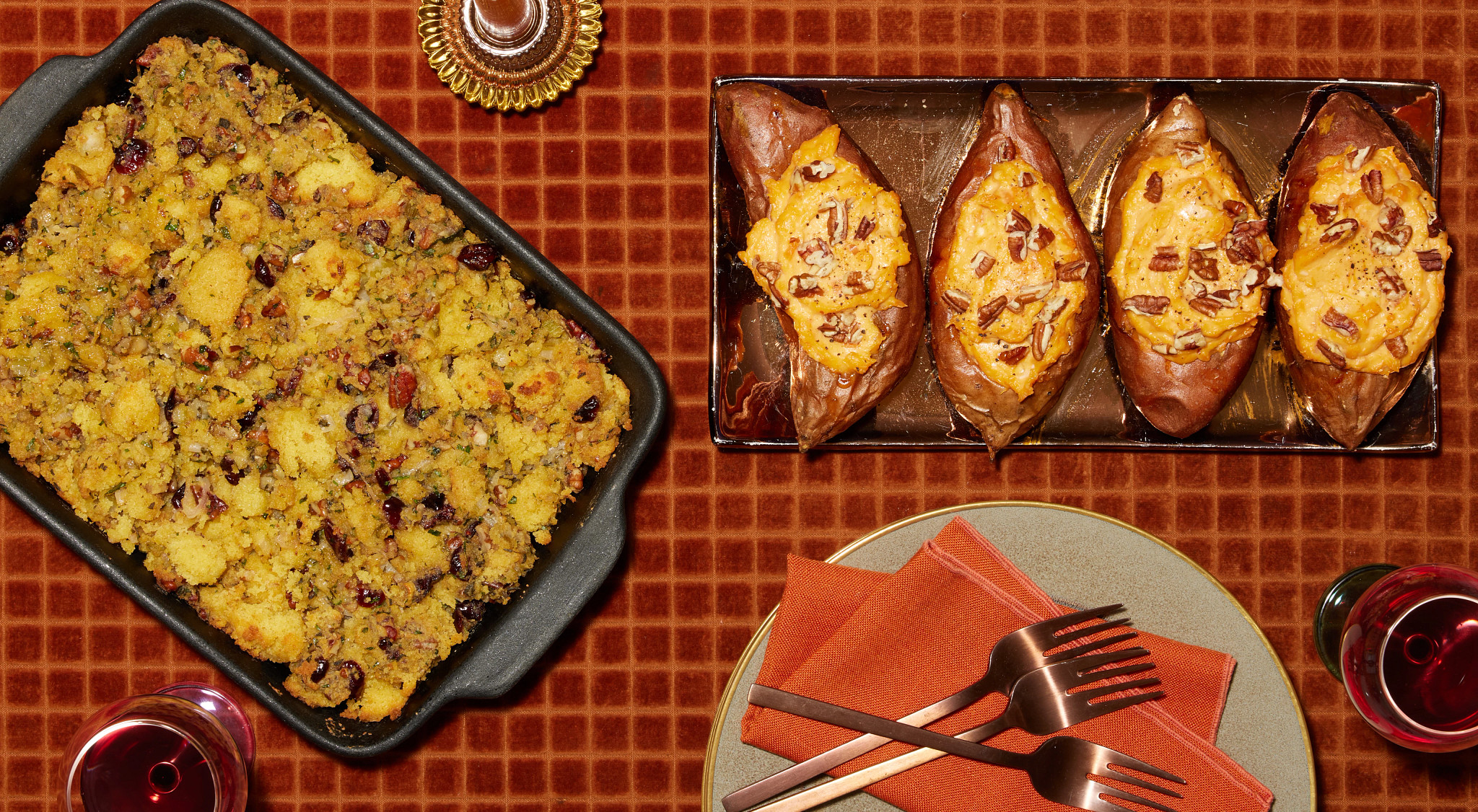 Cornbread stuffing with cranberries, roasted sweet potatoes, and pecans on an orange checkered tablecloth.