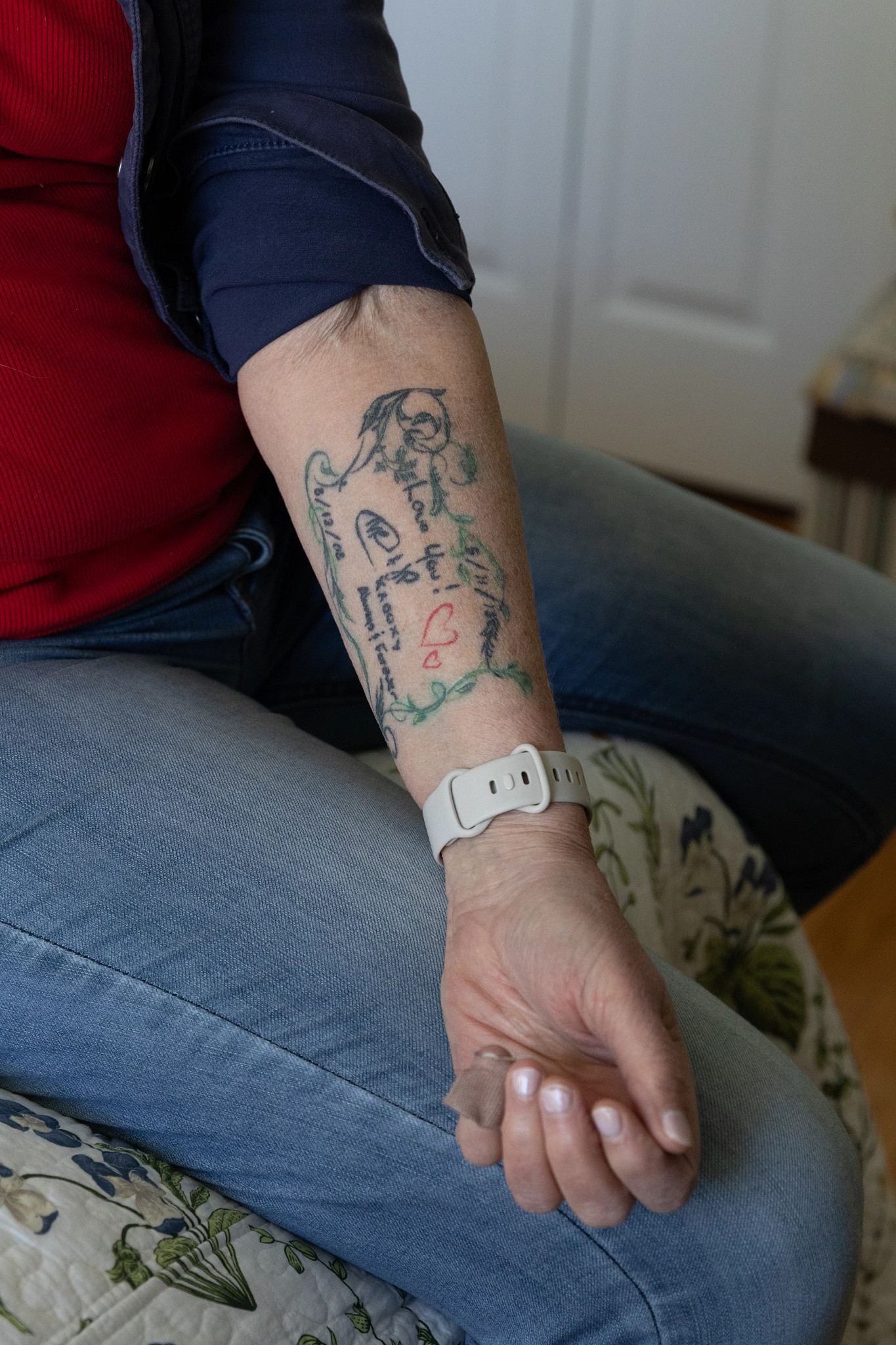 A person's forearm displaying handwriting, dates, and heart tattoos.