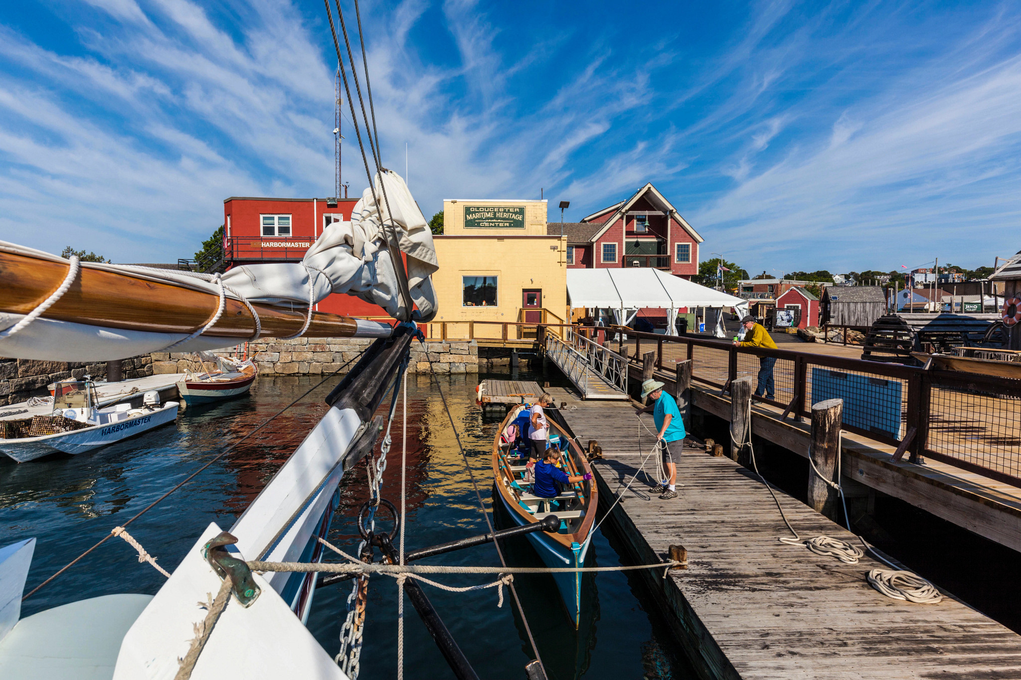 people sitting in a small boat at a dock as a man unravels a rope