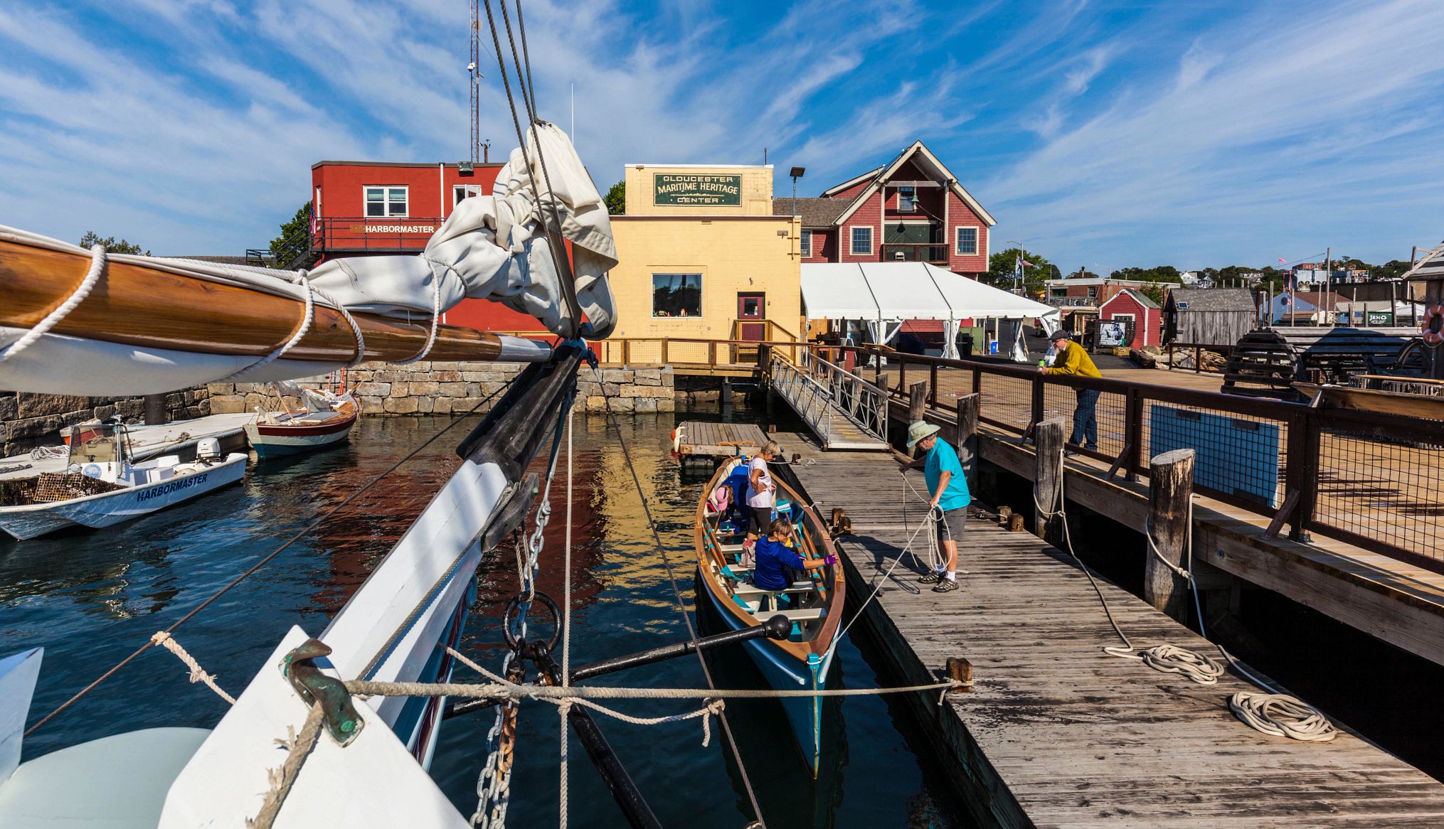 Nostalgic Beach Getaways people sitting in a small boat at a dock as a man unravels a rope