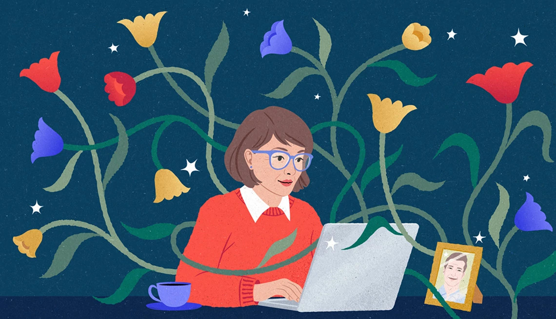 a person working on a computer with flowers around them and a picture frame on a desk