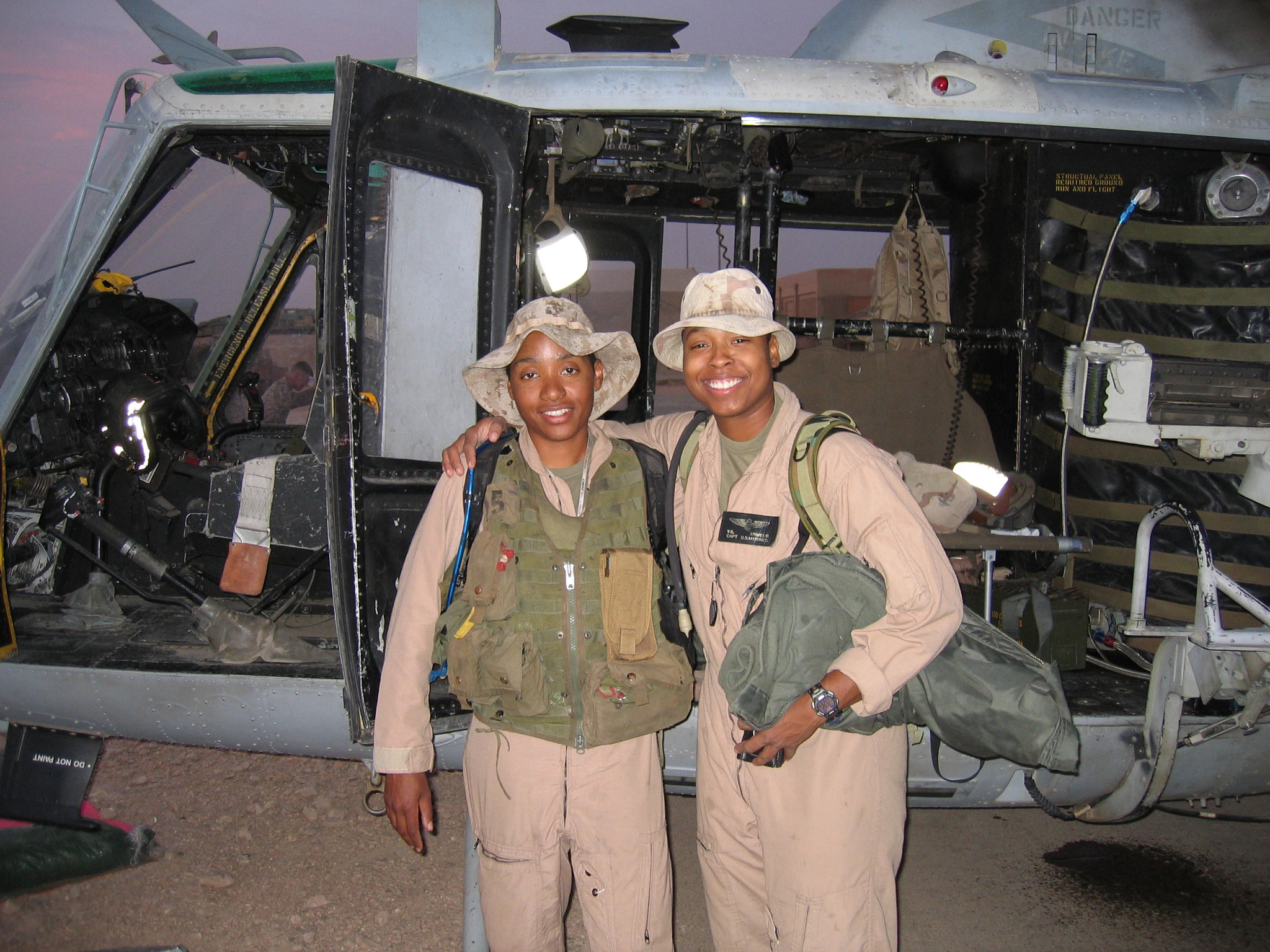 misca gerter and vernice armour, wearing flight suits and combat gear, embracing outside a military helicopter